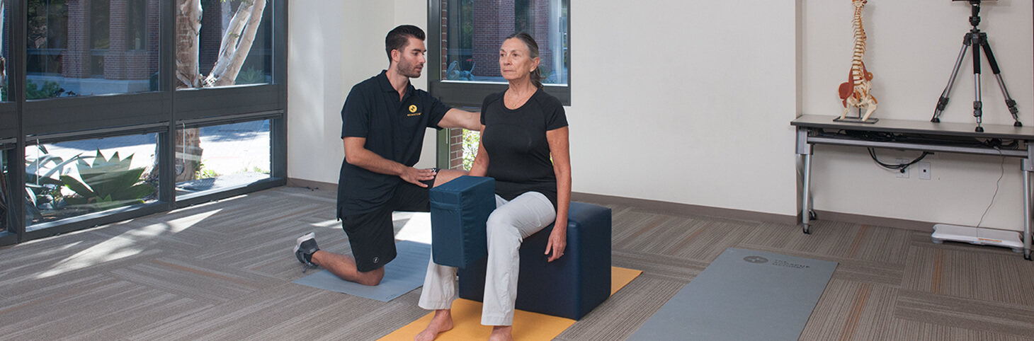 Photo of a woman doing knee exercises with an Egoscue therapist