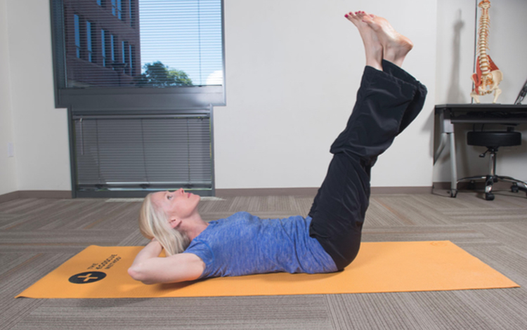 Photo of woman in athletic clothes practicing Egoscue stretches on the floor