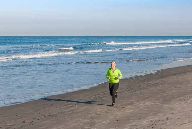 Photo of a woman in athletic clothes jogging on a beach