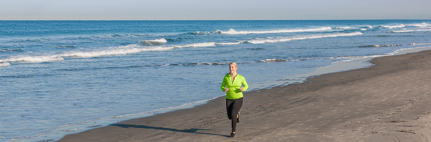 Photo of a woman in athletic clothes jogging on a beach